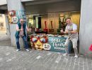 Foto zweier Festbändel-Verkäufer vor ihrem Marktstand. Foto zweier Festbändel-Verkäufer vor ihrem Marktstand.